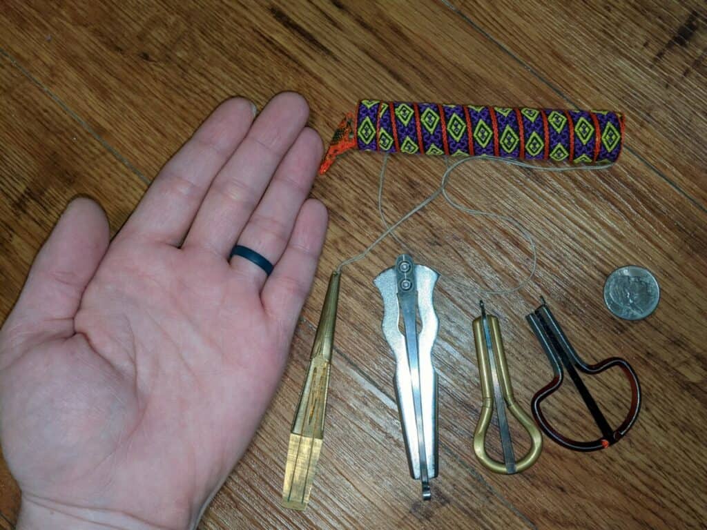 my hand next to a dan moi, bass jaw harp, and two smaller jaw harps as well as a quarter