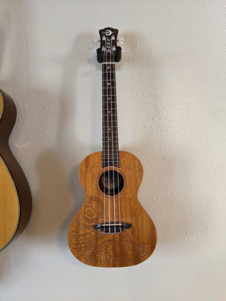 Luna Ukulele hanging on the wall with tattoo pattern.